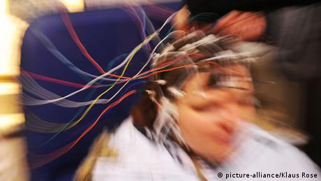 A blurred picture of a person with wires clipped onto their head