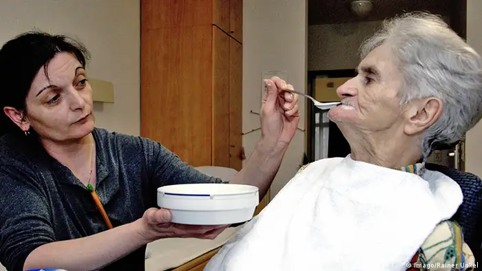 Deutschland Pflegerin füttert eine Seniorin im Altenpflegeheim