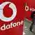 Мужчина говорит по мобиотному ттелефону на фоне рекламы Vodafone