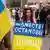 Демонстрация в Берлине. Женщина держит в руках украинский флаг с надписью "Мы вместе остановим войну"