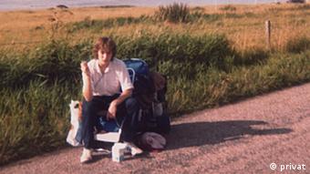 DW's Susanne Spröer sitting by the side of the road, in front of a field.