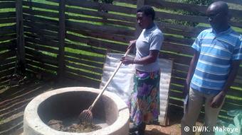 A woman mixes cow dung and water while a man watches