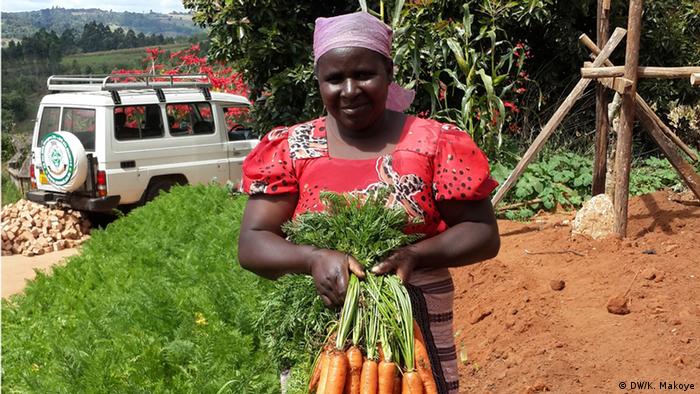 A female farmer proudly holds a bunch of carrots