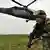 Ein kolumbianischer Soldat beim Kampf gegen die Farc, im Hintergrund ein Helikopter (Foto: DPA)