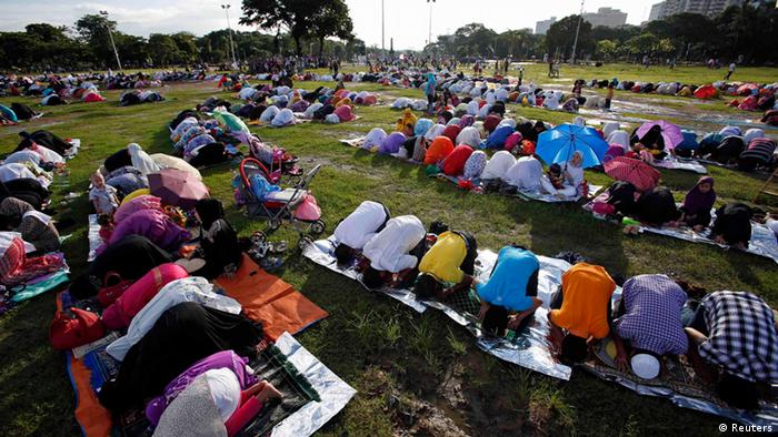 In einem öffentlichen Park haben sich viele Menschen zu einem Gebet versammelt