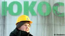 People walk by the Yukos oil company headquarters in Moscow in this July 8, 2004 file photo. The Hague's arbitration court has ruled in favour of a group of shareholders in defunct oil giant Yukos against Russia, awarding compensation of around $50 billion, a source close to the ruling said on July 28, 2014. REUTERS/Viktor Korotayev/Files (RUSSIA - Tags: POLITICS ENERGY BUSINESS CRIME LAW)