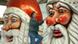 A man cleans two large santa statues A man cleans two large santa statues