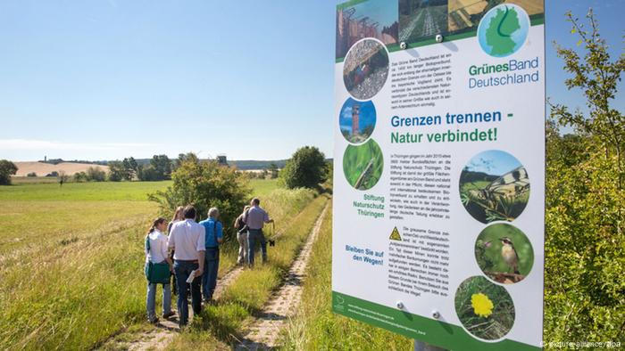 Un grupo de personas pasa por delante de una señal en la reserva natural de Grünes Band.