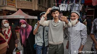Uighur Muslims try on hats at a market in Xinjiang.