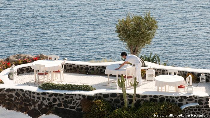 A waiter prepares a table at a restaurant in the island of Santorini, Greece.