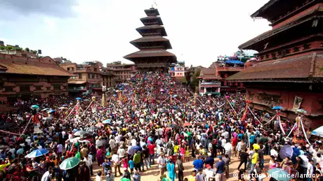 A square in Katmandu full of people celebrating Gaijatra. 