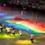 Die Athleten der Gay Games laufen ein und tragen eine große Flagge in Regenbogenfarben auf den Schultern.
