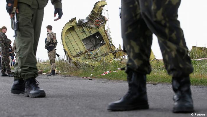Armed pro-Russian separatists stand guard as monitors from the Organization for Security and Cooperation in Europe (OSCE) and members of a Malaysian air crash investigation team inspect the crash site of Malaysia Airlines Flight MH17.