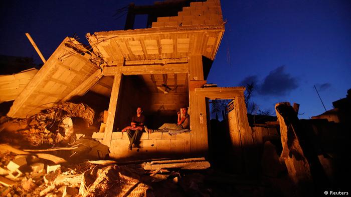 Palestinians sit outside their house. Witnesses said it was heavily shelled by Israel during the offensive, in the Shejaia neighbourhood, east of Gaza City in August 2014.