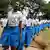 Girls dressed in blue and white school uniforms march in a long line. Photo: Zuberi Mussa
