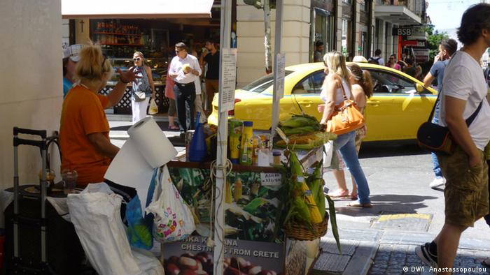A woman sells corn and chestnuts on an Athens street corner