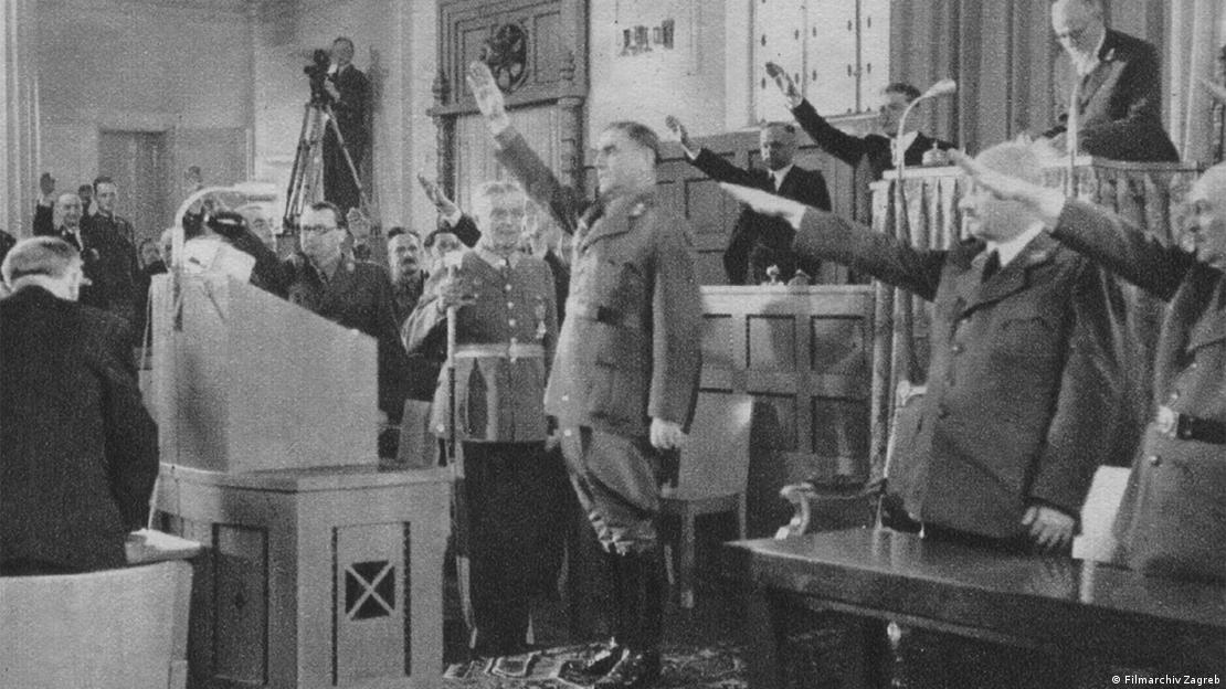 Ante Pavelić (u sredini) i drugi članovi parlamenta pozdravljaju hitlerovim pozdravom sa ispruženom i uzdignutom rukom Ante Pavelić (u sredini) i drugi članovi parlamenta pozdravljaju hitlerovim pozdravom sa ispruženom i uzdignutom rukom