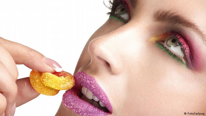 Buntgeschminkte Frau isst Süßigkeiten