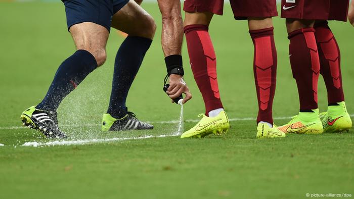 The referee draws a spray line on the football field, marking the place for the free kick
