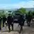 Bewaffnete Polizisten durchstreifen eine ländliche Schotterstraße.(Foto: picture-alliance/dpa/efe)