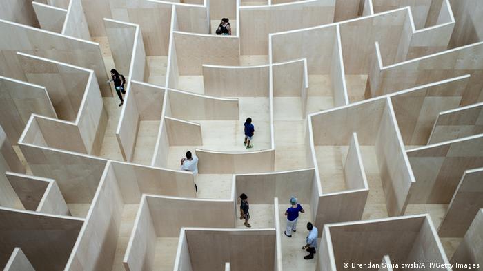 Blick auf ein Labyrinth, in dem mehrere Menschen umherlaufen