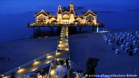Sellin Pier lit up at night with the lights reflected in the water