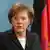 German Chancellor Merkel speaking at a podium in front of the German flag