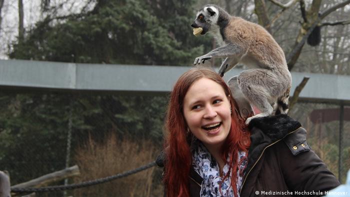 A woman with a lemur on her shoulder