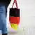 A woman carrying a bag in the colors of the German flag