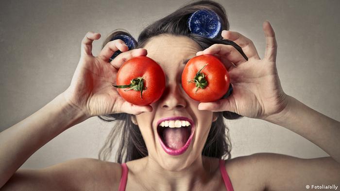 Eine Frau mit Lockenwicklern in den Haaren hält sich Tomaten auf die Augen. (Symbolbild) (Fotolia/olly)