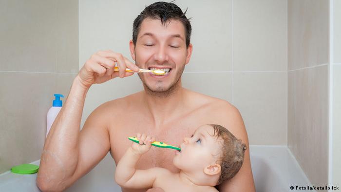A man and baby brush their teeth