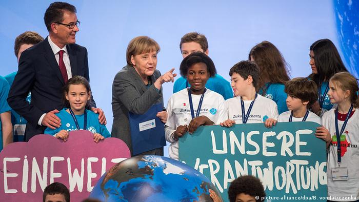 Entwicklungsminister Gerd Müller und Angela Merkel mit Kindern auf der Bühne (Bild: dpa)