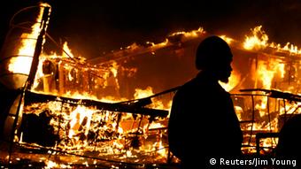 A man watches a burning building after a grand jury returned no indictment in the shooting of Michael Brown in Ferguson, Missouri November 24, 2014.
