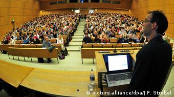 A professor lecturing to a packed room of students. (Photo: Jan-Philipp Strobel/dpa)