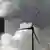Ветрогенератор на фоне дымящей трубы угольной электростанции