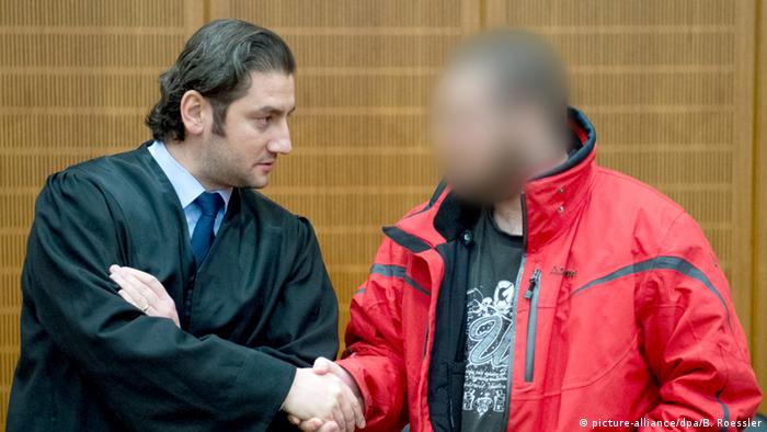 Kurz bevor ihn das Gericht zu einer Haftstrafe von drei Jahren und neun Monaten verurteilt, begrüßt Kreshnik B. seinen Anwalt Mutlu Günal vor der Anklagebank in einem Hochsicherheitssaal des Oberlandesgerichts in Frankfurt (Copyright: Boris Roessler/dpa )
