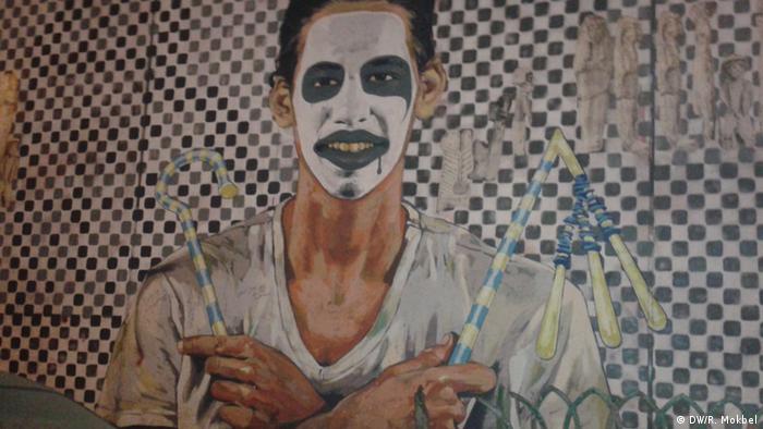 This painting shows a man with a clown mask holding ancient Egyptian scepters of kinship.