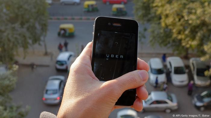 Smartphone mit Uber-Schriftzug; im Hintergrund ein Parkplatz (Foto: AFP/Getty Images/T. Bahar)