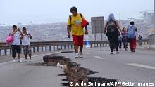 People walk along a cracked road in Iquique, northern Chile, on April 2, 2014 a day after a powerful 8.2-magnitude earthquake hit off Chile's Pacific coast. An 8.2-magnitude earthquake hit Chile late Tuesday, killing at least six people and generating tsunami waves that might ripple as far as Indonesia. AFP PHOTO / ALDO SOLIMANO (Photo credit should read Aldo Solimano/AFP/Getty Images)