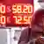Женщина на фоне вывески с курсами валют в обменном пункте
