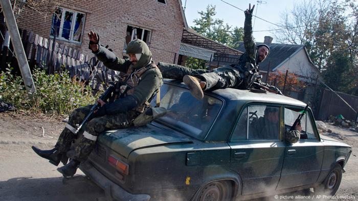 Pro-Russian rebels ride atop a car