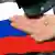 Монета в руке на фоне российского флага 