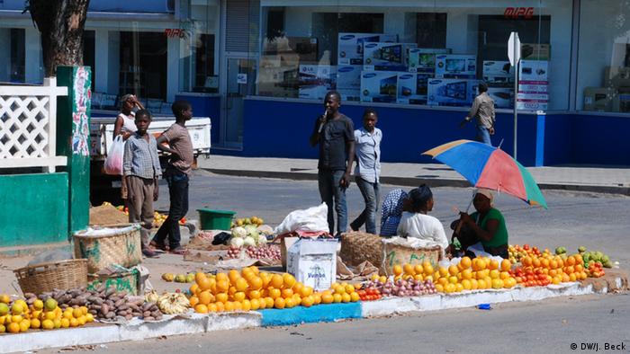 People sell produce on a sidewalk in Mozambique