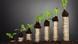 Столбики из монет с зелеными ростками, символизирующие экономический рост Столбики из монет с зелеными ростками, символизирующие экономический рост