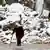 Ein Mann geht an schneebedeckten Trümmern im syrischen Aleppo vorbei (Foto: rtr)