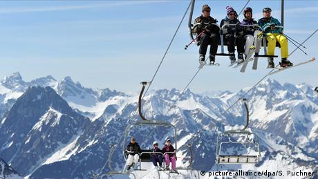 Ein Sessellift mit Skifahrern schwebt den Berg hinauf 