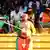 A Cameroonian football fan holding a flag and painted in the colors of gis flag