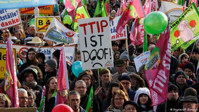 German farmers and consumer rights activists hold banners and flags as they protest against the Transatlantic Trade and Investment Partnership (TTIP), mass husbandry and genetic engineering during a demonstration in Berlin, January 17, 2015. The banner in the center reads TTIP is dumb. REUTERS/Fabrizio Bensch