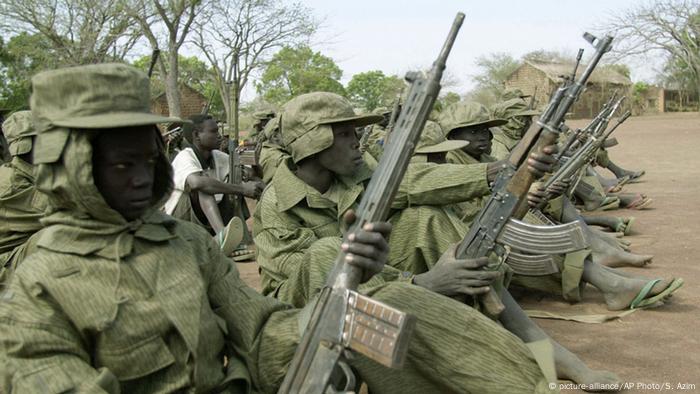 Sudenasische Kindersoldaten sitzen nebeneinander und halten ihr Maschinengewehr in der Hand. (Foto: picture-alliance/AP Photo/S. Azim)
