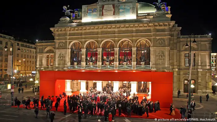 Die vollkommen illuminierte Wiener Staatsoper im Rampenlicht. Der Eingangsbereich ist mit roten Teppichen umrandet. Unzähliche Gäste und Fotografen tummeln sich vor dem Portal. (Foto:picture-alliance/dpa/EPA/G. Hochmuth) 